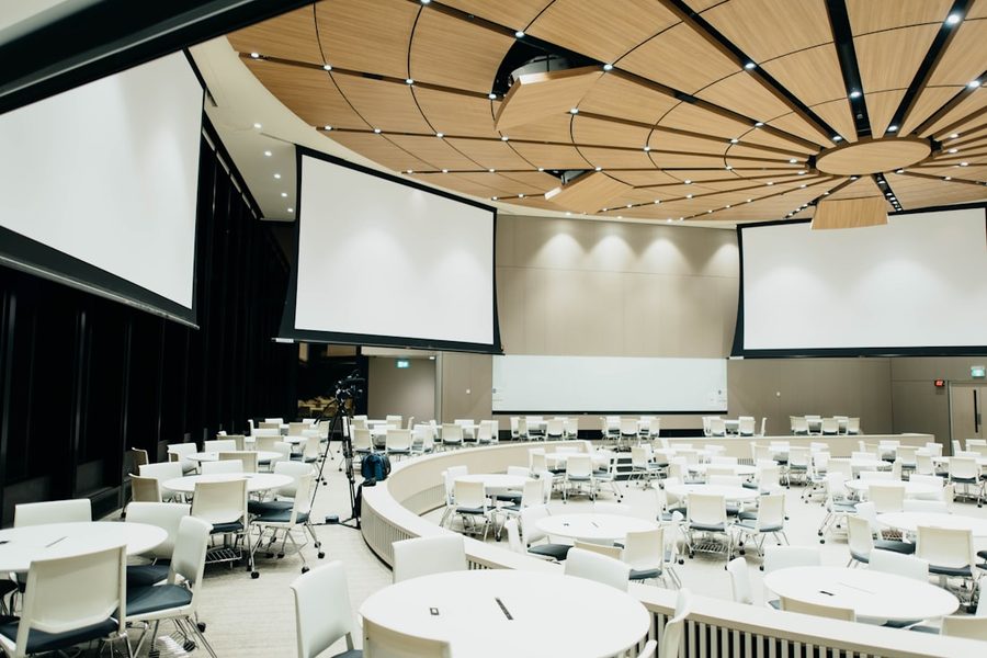 Large conference room with screens and round tables, ready for a meet-up