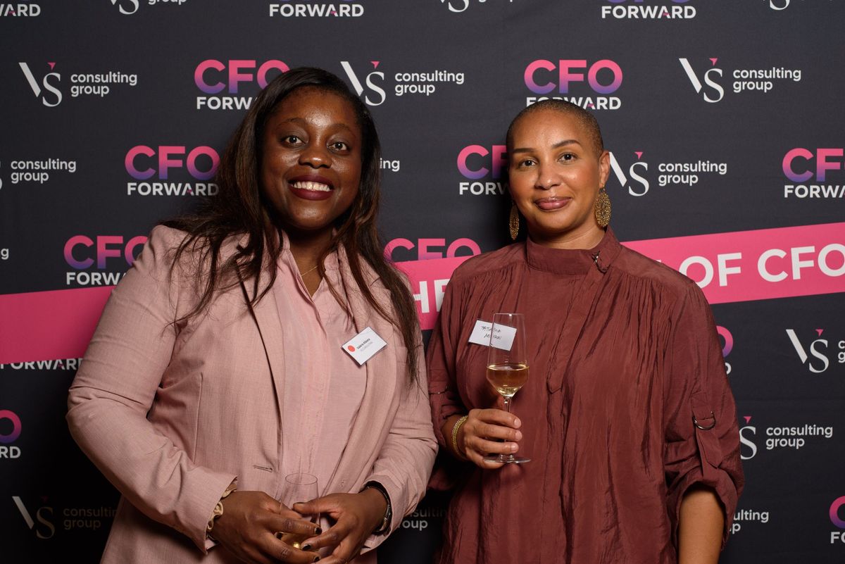 Two guests in front of the CFO Forward and VS Consulting Group wall